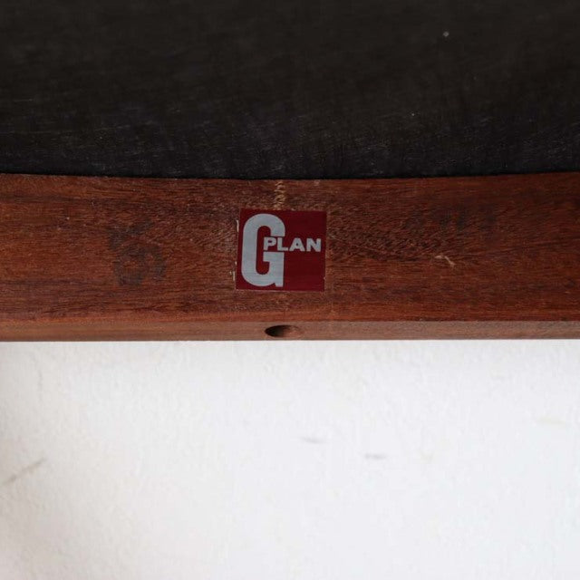 Close-up of G-plan logo on vintage teak wood frame, showcasing mid-century British craftsmanship and rich wood grain.