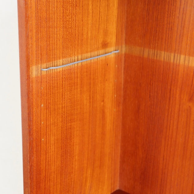 Close-up of vintage mid-century teak wood corner panel with visible grain and smooth finish, custom iron leg detail hinted.