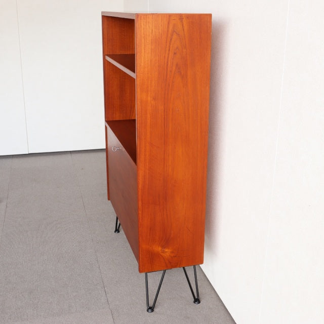 Vintage mid-century Danish teak shelving unit with sleek iron legs, rich wood grain, and minimalist form.