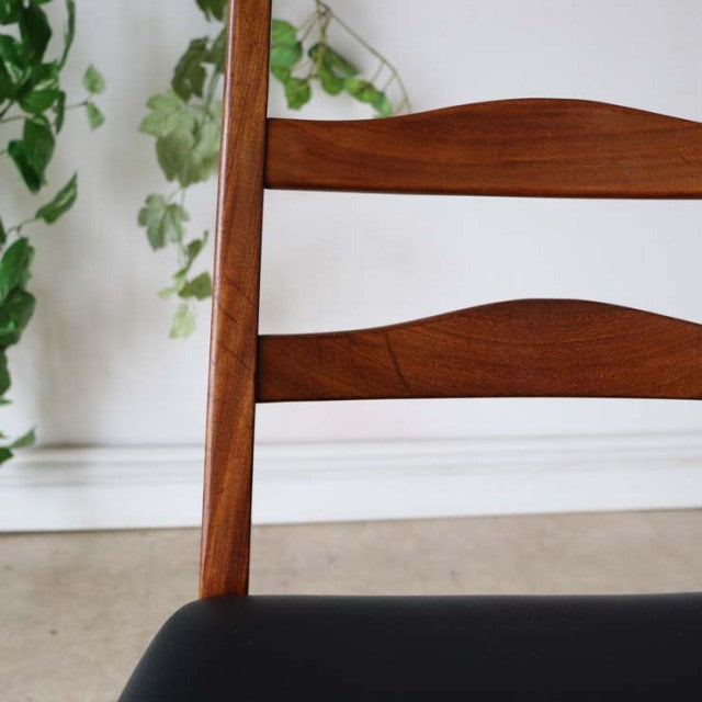 Set of four vintage British mid-century G-Plan dining chairs in teak with curved ladder back and black cushioned seats.