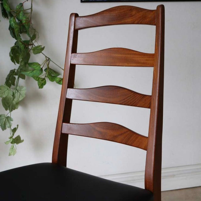Set of four vintage G-Plan ladder back dining chairs in mid-century British teak with curved slats and black seats.