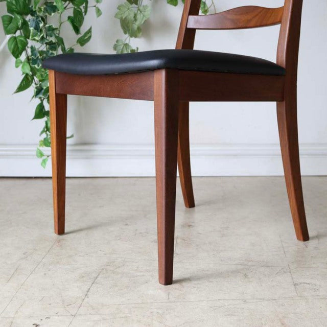 Set of four vintage British mid-century teak ladder back dining chairs with black upholstered seats and tapered legs.