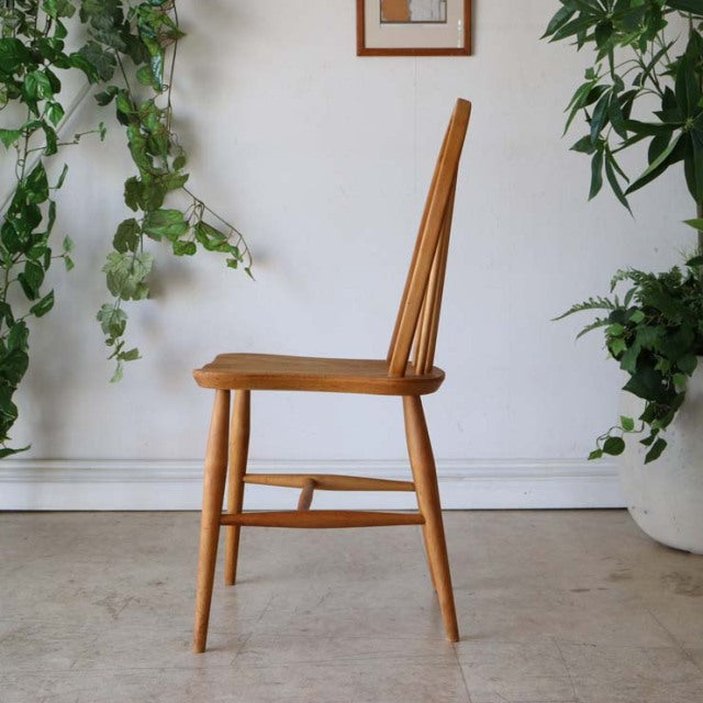 Mid-century British Ercol Hoopback chair in natural teak with visible wood grain, slender tapered legs, and curved spindle.