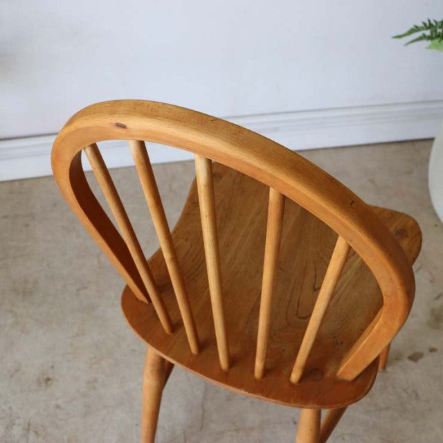 Vintage British mid-century teak Ercol hoop back dining chair with curved spindles and smooth wood grain.