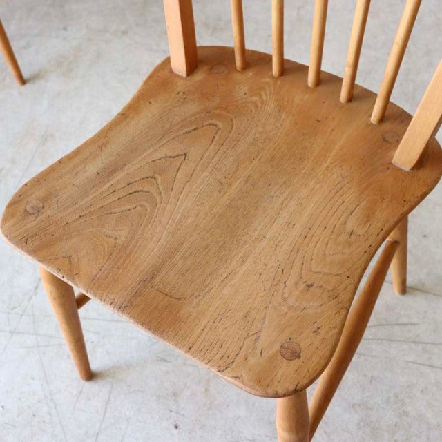 Natural teak wood ERCOL Hoopback chair seat showing smooth grain, rounded edges, and slender turned legs in mid-century.
