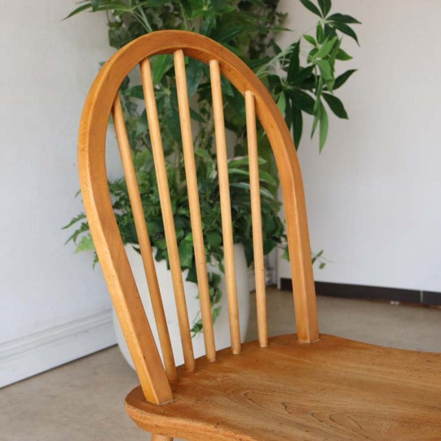 Vintage mid-century British Ercol hoop-back dining chair in solid teak with visible wood grain and slender spindled backrest.