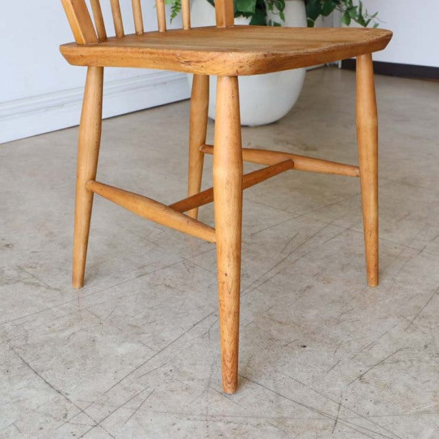 Mid-century British ERCOL dining chair in vintage teak with smooth rounded legs and spindle backrest showing natural wood.
