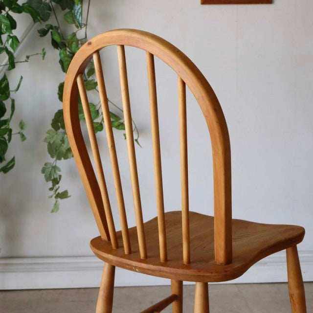 Vintage British mid-century Ercol hoop-back chair in warm teak with smooth wood grain and slender spindled backrest.