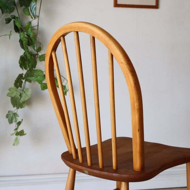 Set of four mid-century British ERCOL Hoopback chairs in natural teak with curved spindle backs and smooth wood grain seats.