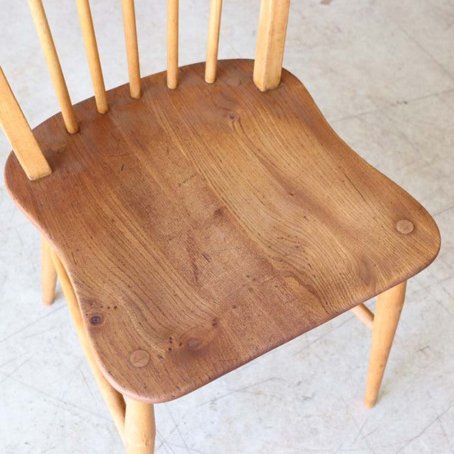 Set of four vintage mid-century ERCOL Hoopback chairs in natural teak with curved spindled backs and smooth, contoured seats .