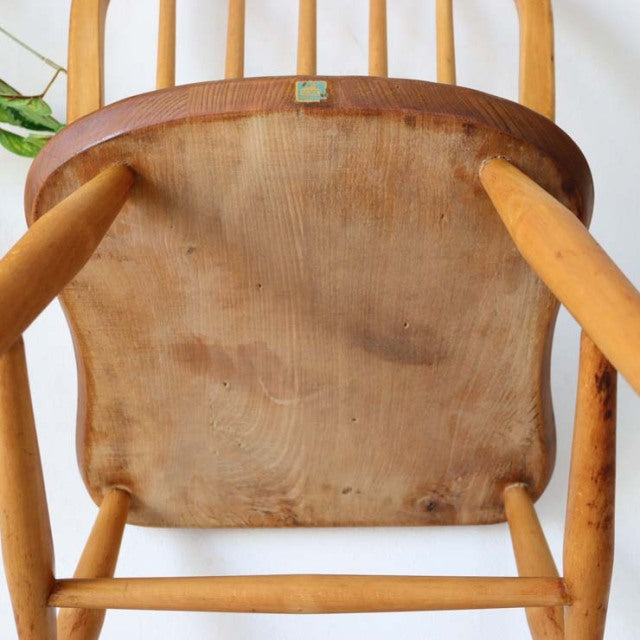 Underside of vintage mid-century British Ercol Hoopback chair showing smooth teak wood grain, rounded legs, and natural.