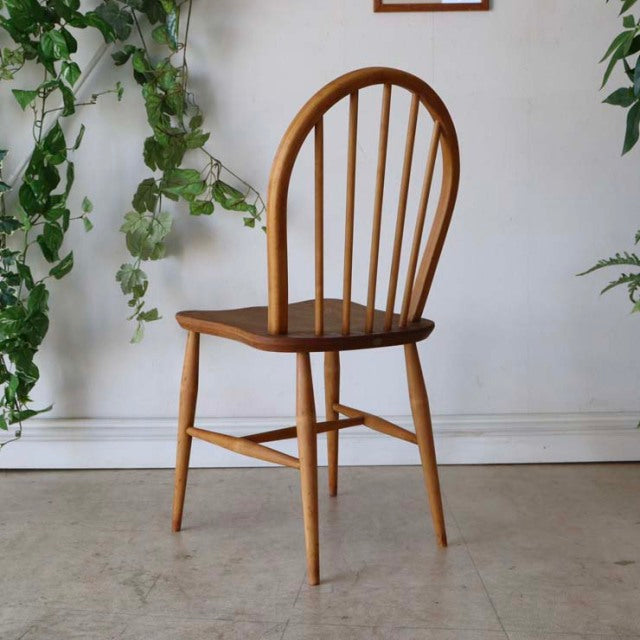 Vintage British mid-century Ercol hoop back dining chair in warm teak with visible wood grain and slender tapered legs.