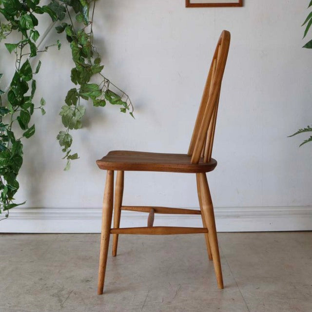 Vintage teak mid-century British Ercol hoop back dining chair with slender turned legs and smooth wood grain.
