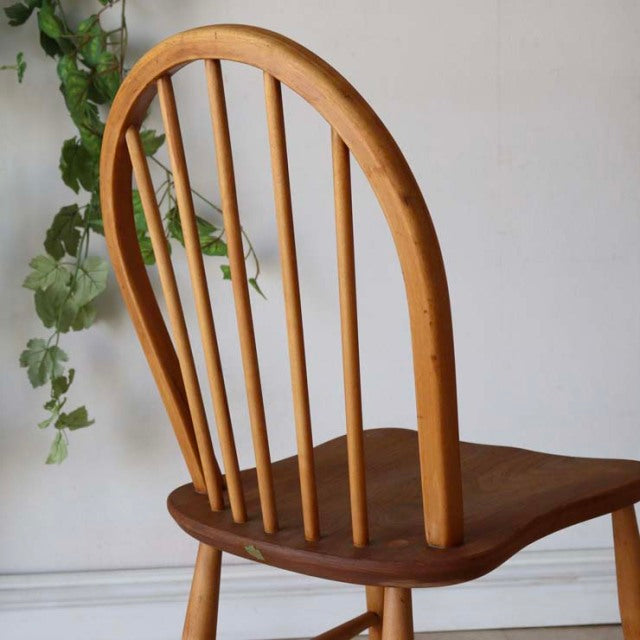 Vintage British mid-century Ercol hoop back dining chair in solid teak with smooth curved backrest and rounded wood grain.