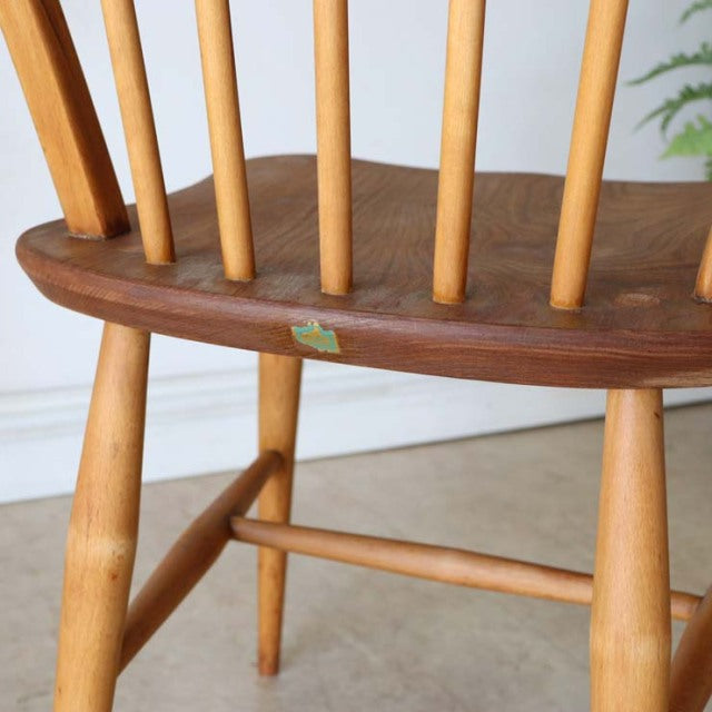Vintage British mid-century Ercol hoop-back chair in teak with natural wood spindles and visible rich wood grain on the seat .