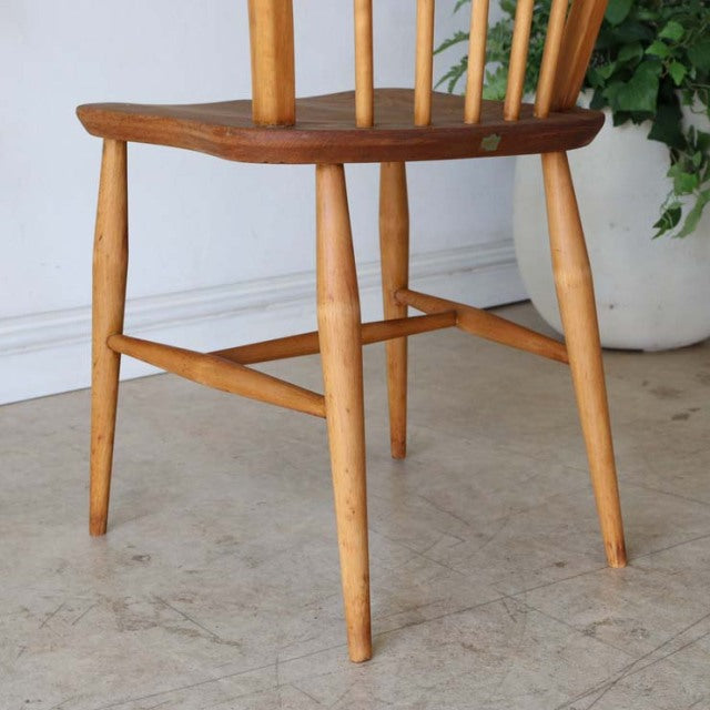 Mid-century British vintage Ercol hoop back chair with teak seat, light spindle legs, and visible wood grain.