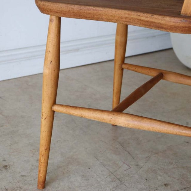Mid-century British vintage teak Ercol hoop back dining chair leg and stretcher detail with smooth wood grain and light.