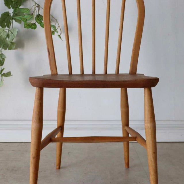 Vintage teak Ercol hoop back dining chair with curved spindle backrest, smooth wooden seat, and tapered legs, showcasing.