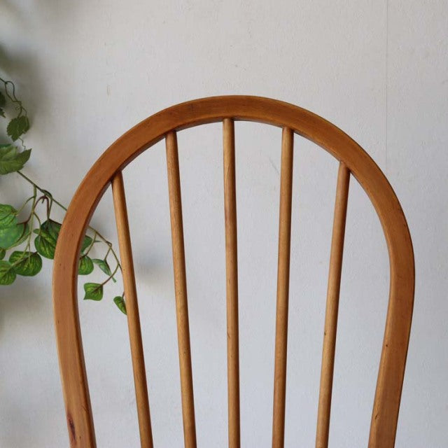 Vintage British mid-century Ercol hoop-back dining chair in warm teak with slender vertical spindles and smooth curved top.