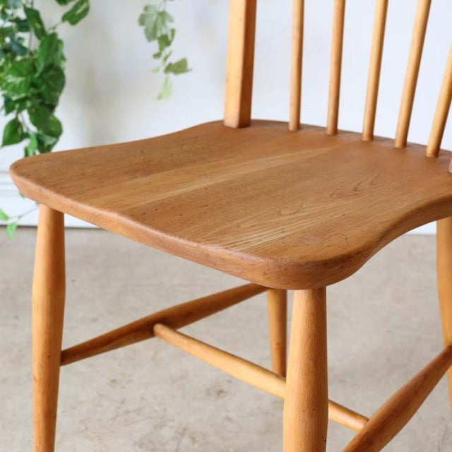 Vintage mid-century British Ercol hoop back dining chair in light teak with smooth curved seat and slender spindle backrest.