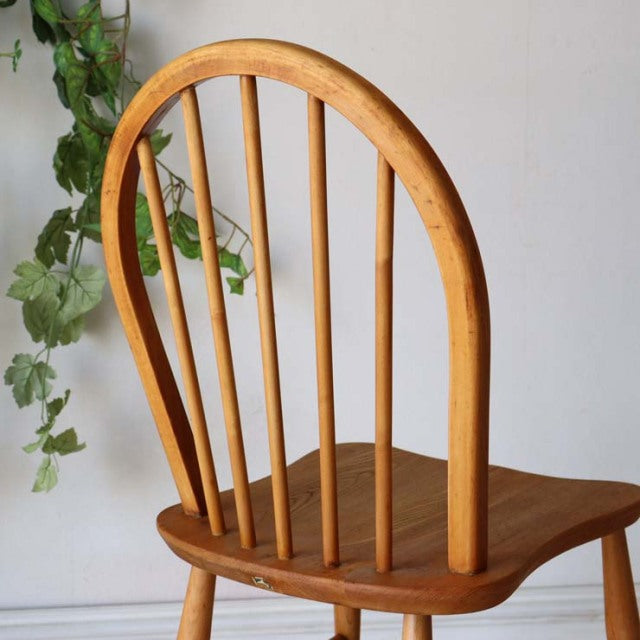 Vintage teak mid-century British Ercol hoop back dining chair with curved spindle back and smooth wood grain seat.