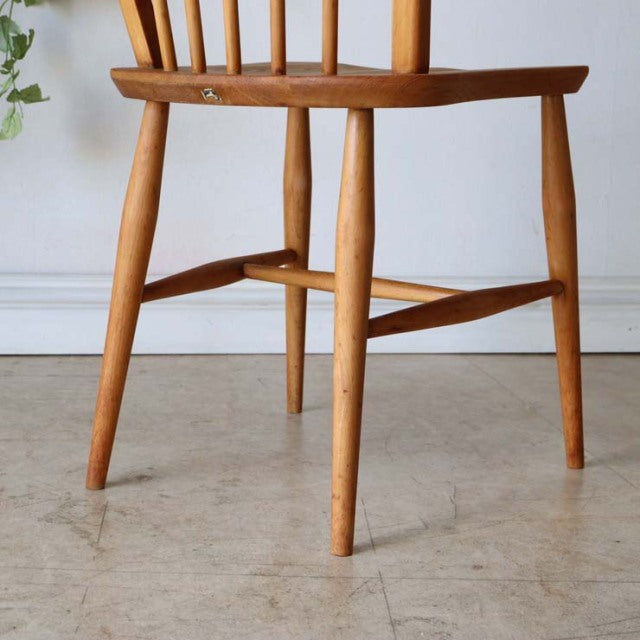 Set of four vintage ERCOL Hoopback dining chairs in natural teak with mid-century British design, visible wood grain,.