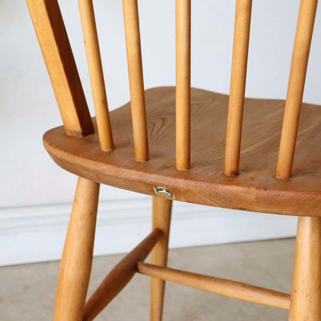 Vintage British Ercol hoop back dining chair in smooth teak with spindle legs and visible wood grain.