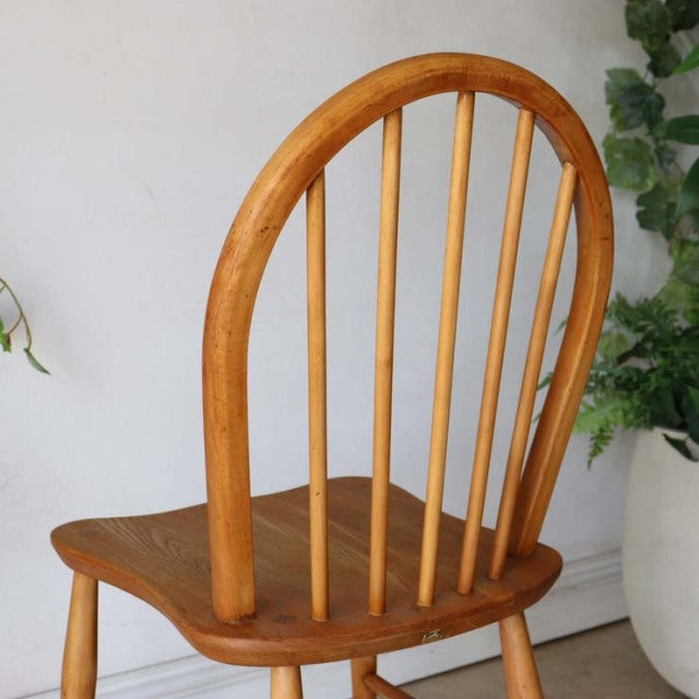Mid-century British vintage Ercol hoop back chair in teak with curved spindle backrest and rounded legs, showing rich wood.