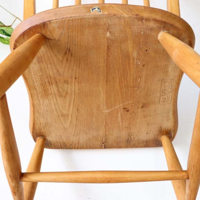 Vintage British mid-century teak Ercol hoop-back chair showing wood grain underside and turned legs.