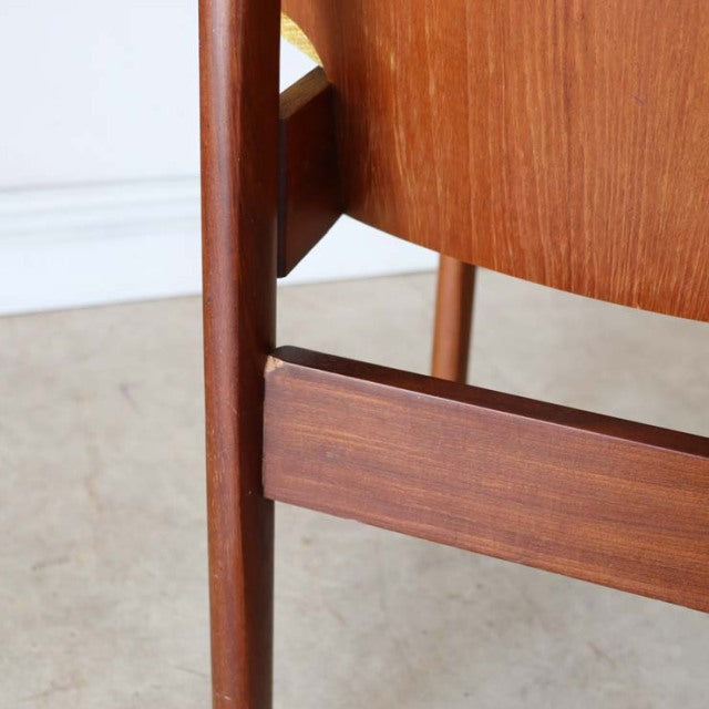 Close-up of vintage British mid-century teak dining chair leg and frame with warm wood grain and smooth finish.