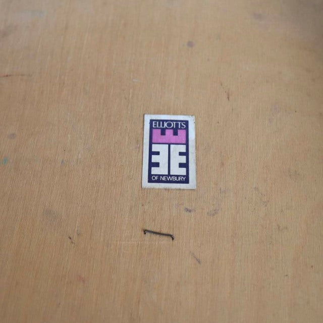 Close-up of Elliottts of Newbury vintage British mid-century teak dining chair label on light wood surface with small dark.