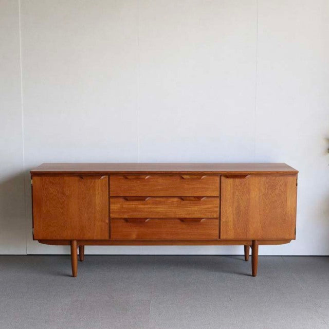 Vintage mid-century teak sideboard by Austinsuite with rich wood grain, three central drawers, two cabinet doors, and.