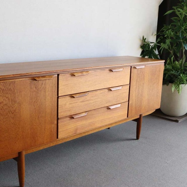 Mid-century British teak sideboard by Austinsuite with rich wood grain, three central drawers, and two cupboard doors on.