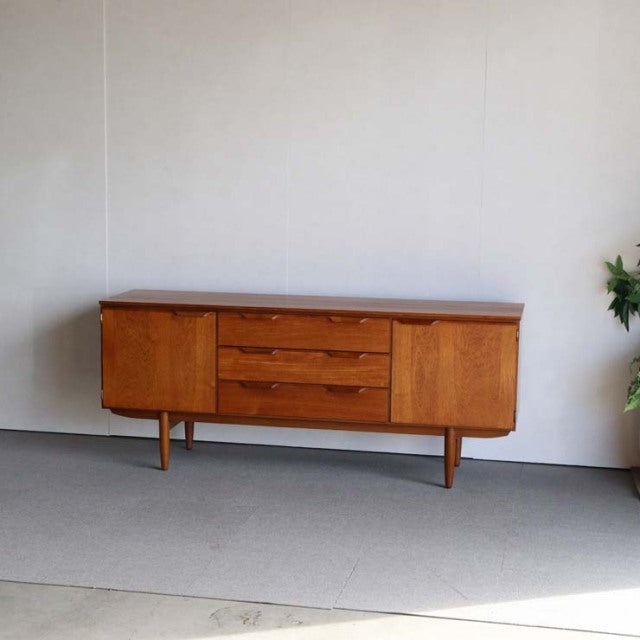 Mid-century vintage teak sideboard by Austinsuite with rich wood grain, tapered legs, three central drawers, and two side.