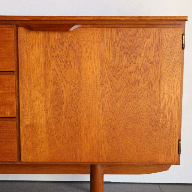 Vintage mid-century teak sideboard with rich wood grain, British-Danish design, slender tapered legs.