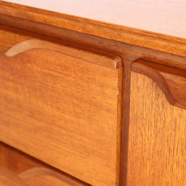 Close-up of vintage British mid-century Austinsuite teak sideboard door with smooth wood grain and curved handle detailing.
