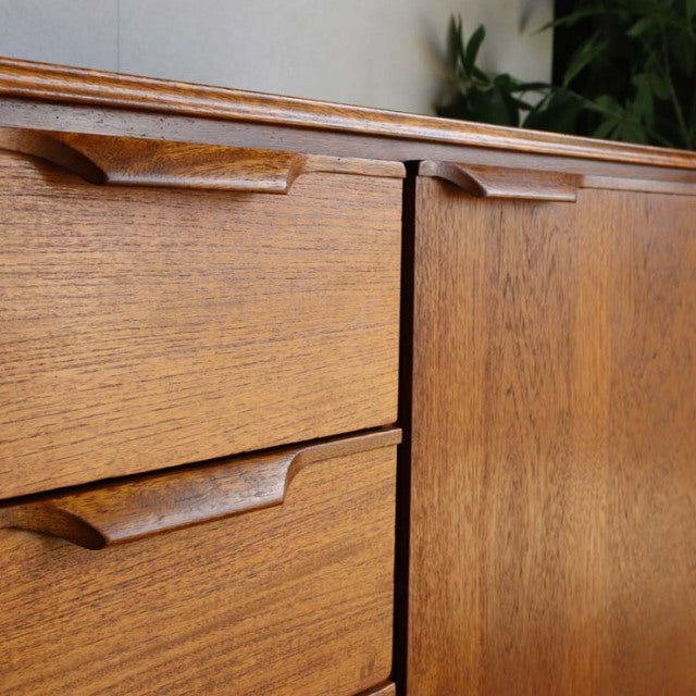 Vintage teak sideboard by Austinsuite featuring British mid-century design, smooth wood grain, and sculpted drawer handles.