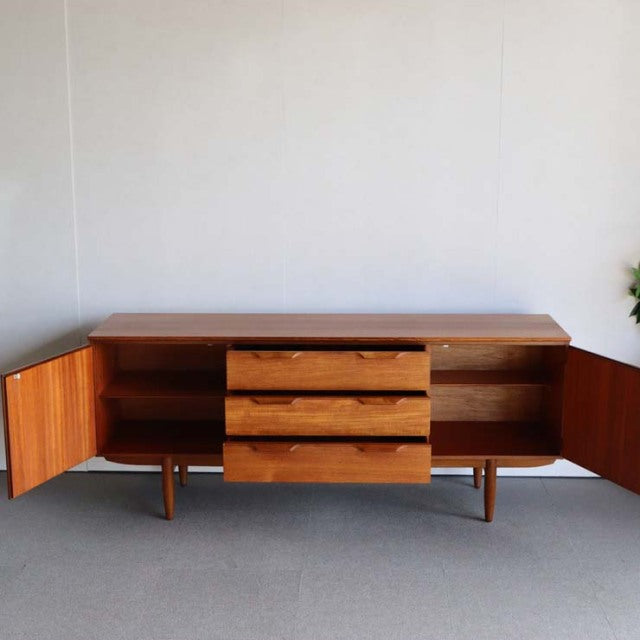 Vintage teak Austinsuite mid-century sideboard with three center drawers, two open side cabinets, tapered legs, and visible.