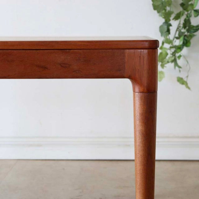 Mid-century Danish vintage teak dining table corner with rounded edges and tapered legs showing rich wood grain.
