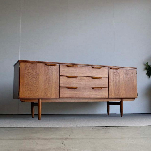 Vintage mid-century teak sideboard by Austinsuite, British-Denmark design with rich wood grain, tapered legs, and recessed.