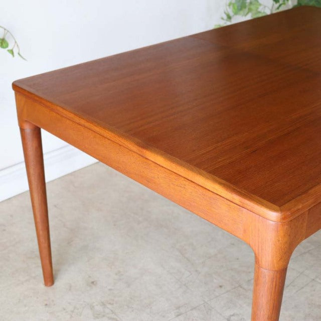 Mid-century vintage Danish teak dining table with smooth wood grain and tapered rounded legs.