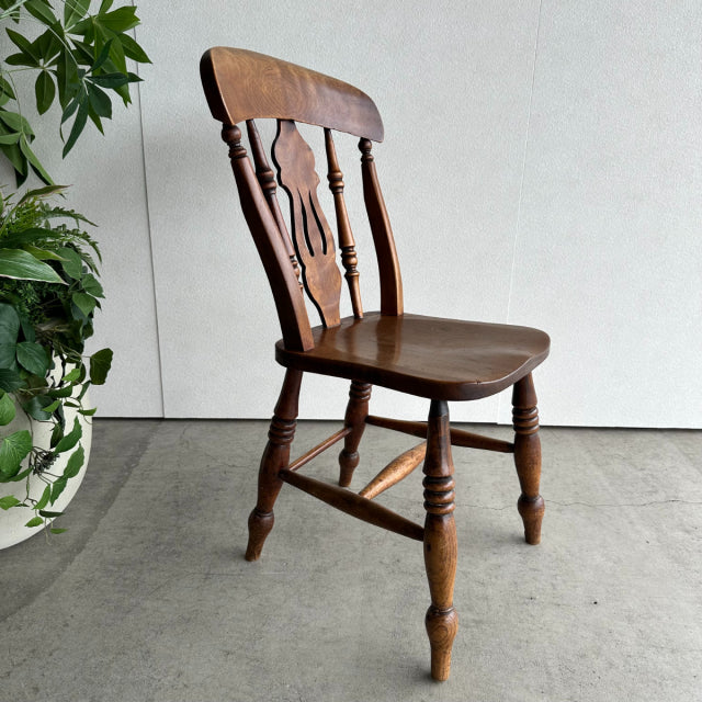 Vintage British teak dining chair with curved slatted back, turned legs, and dark wood grain finish.