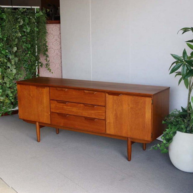 Vintage teak British mid-century Austinsuite sideboard with smooth wood grain, tapered legs, and clean rectangular form.