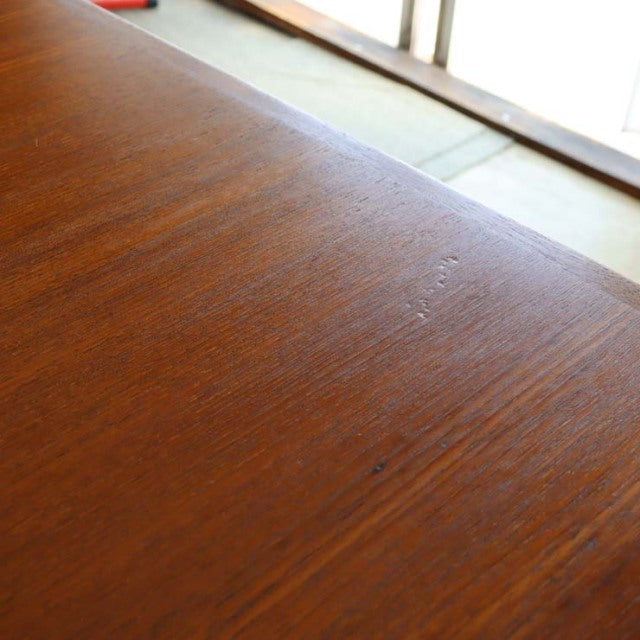 Close-up of vintage mid-century Danish teak dining table surface showing rich wood grain and smooth finish.