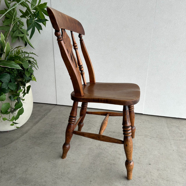 Vintage British teak kitchen chair with turned legs, spindle backrest, and smooth curved seat in mid-century style.