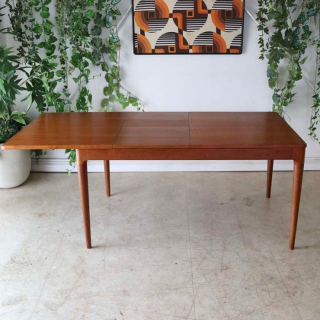Mid-century vintage Danish teak dining table with rectangular top, slender tapered legs, and rich wood grain.