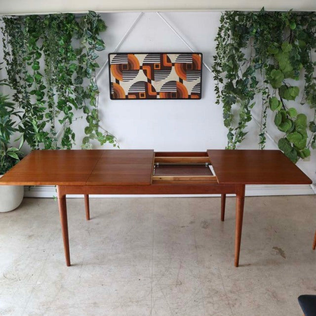 Mid-century vintage teak dining table from Denmark with rich wood grain, tapered legs, and extendable top panel.