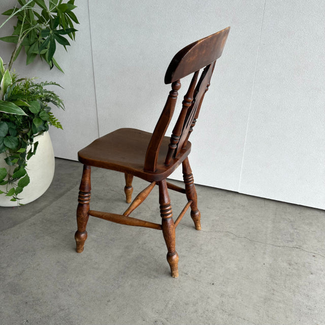Vintage British mid-century kitchen chair in teak with turned legs and spindled backrest, angled for comfort.