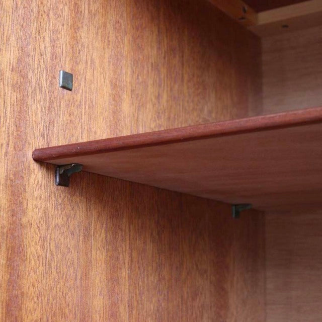 Mid-century British teak sideboard interior showcasing smooth wood grain and sturdy shelf brackets.