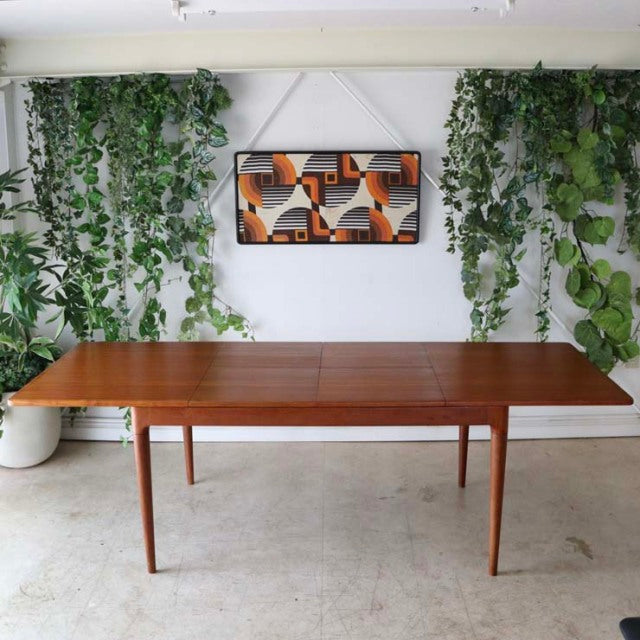Mid-century vintage Danish teak dining table with rich wood grain, tapered legs, and rectangular top.